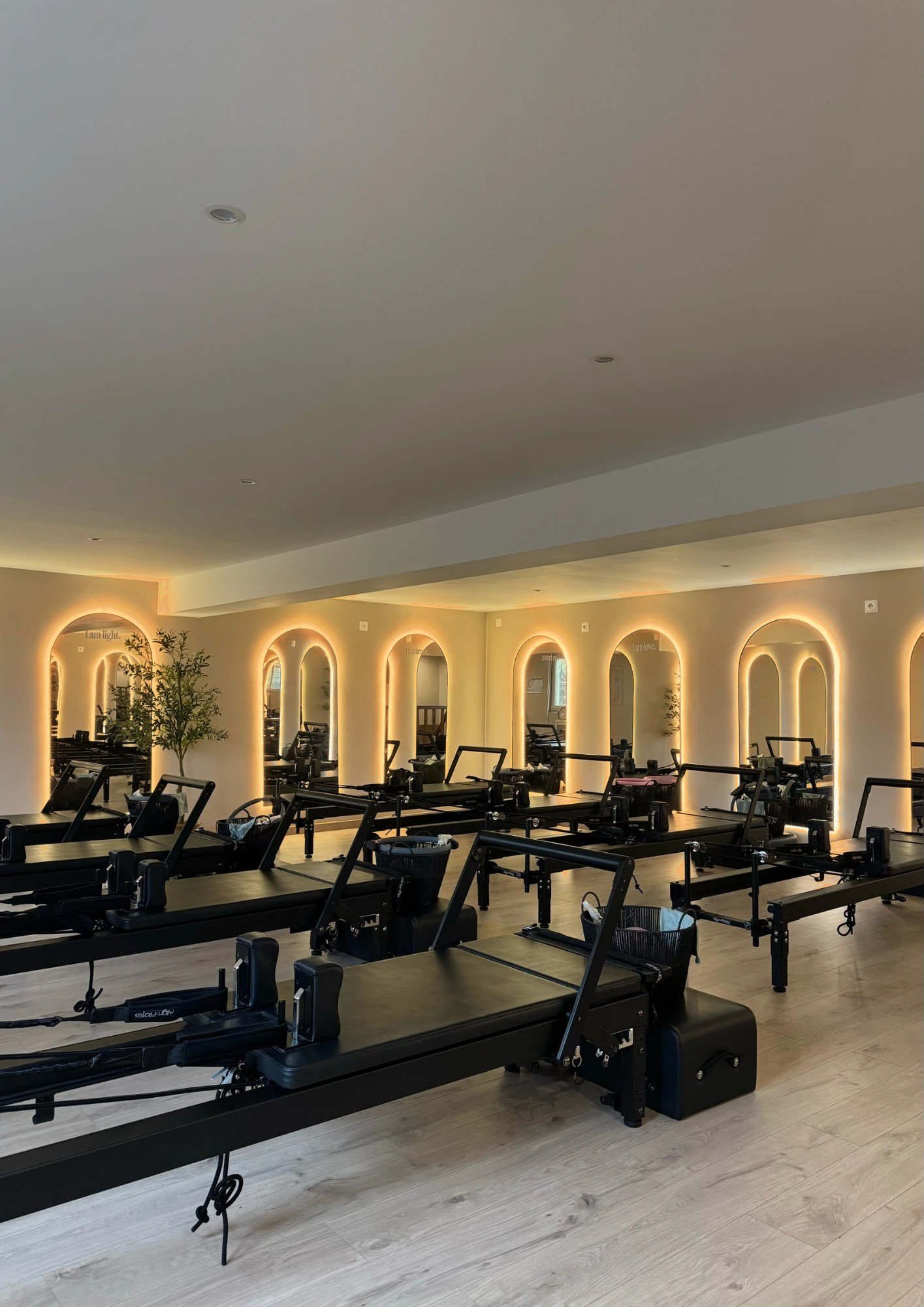 La salle du Jolla Pilates Club : Reformers alignés devant les miroirs en arche rétroéclairés
